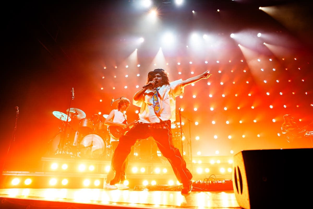 Remi Wolf performing under vivid orange and red concert lights